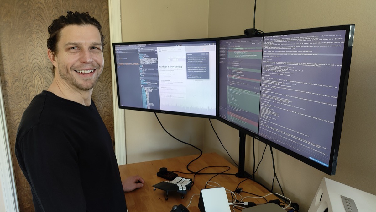 Developer at a desk with triple monitors showing code and the MimicScribe website